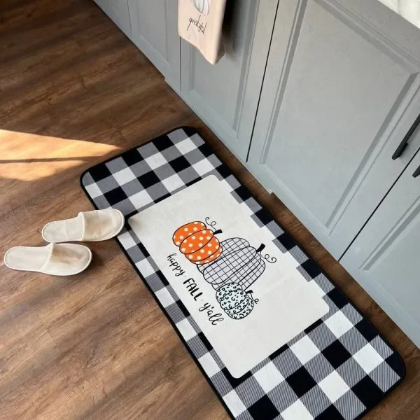 پادری آشپزخانه طرح Happy Fall با سه کدو رنگی و نوشته Happy Fall Y’all مقابل کابینت‌های طوسی