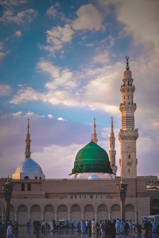 نمای مسجد با گنبد سبز و گنبد آبی زیر آسمان ابری